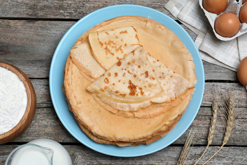 Delicious crepes and ingredients on wooden table, flat lay