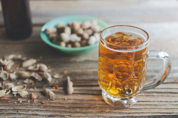 Happy hour with a mug of beer and peanuts in the shell on a rustic wooden background