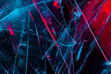Close-up photo texture of blue and red toned broken and cracked glass on black backdrop.