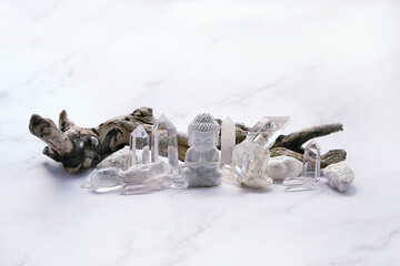 Clear quartz minerals and Buddha statue on light marble background. gemstones crystals for healing...