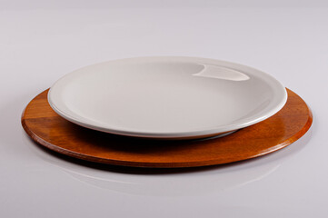 White crockery plate on wooden supla on white infinite background