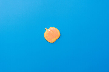 Fototapeta premium Sweet homemade pumpkin cookie with icing isolated on dark blue background minimal flat lay composition.