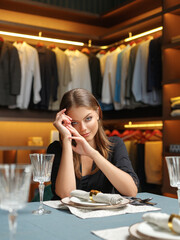 an attractive young girl sits at a table in a boudoir.