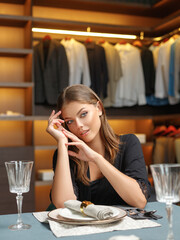an attractive young girl sits at a table in a boudoir.