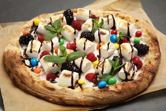 Tasty sweet pizza with berries, marshmallows and candies on black table, closeup