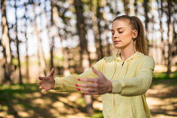 Beautiful woman enjoys exercising Tai Chi in the nature. - obrazy, fototapety, plakaty