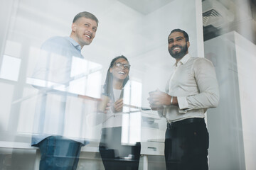 Naklejka na ściany i meble Cheerful people laughing while collaborating and discussing creative ideas for development startup project, professional team of joyful executive managers talking about business strategy of company