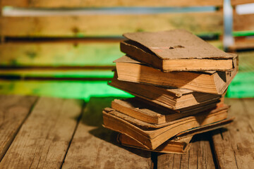 Stack of very dusty, antique books on wooden board with blurred background