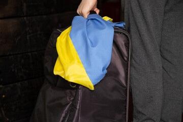 A Ukrainian woman with a suitcase and a flag of Ukraine leaves her home because of the war, Ukrainian refugees, leave