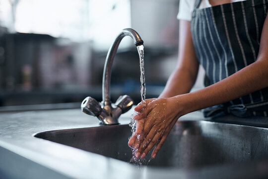 Good food starts with good hygiene. Cropped shot of a woman washing her hands in the sink of a commercial kitchen.