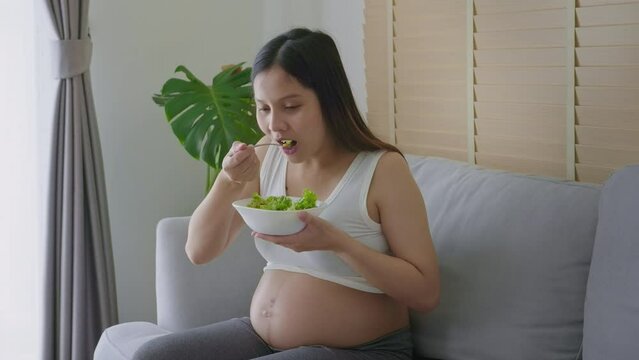Young pregnant woman having salad at home, healthcare and pregnancy care