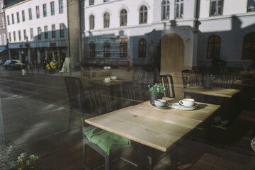 Empty coffee cups in a restaurant through the window with flowers on the wooden table