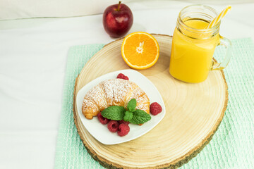 Coffee, orange juice and a croissant on a wooden stalk