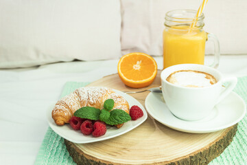 Coffee, orange juice and a croissant on a wooden stalk