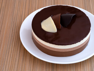 White plate with a chocolate mousse cake on bamboo napkin