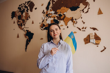 Woman holding a yellow and blue flag of Ukraine on a background world map