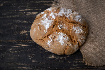 Fresh homemade bread with burlap napkin on dark background. Top view. Rustic style