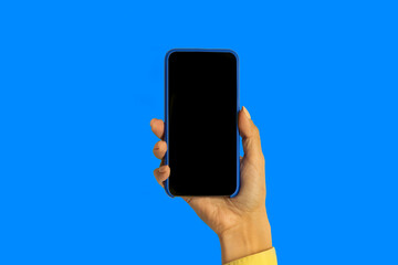 A woman's hand holding a smartphone in a blue case with a black screen, isolated on a blue background, cutting off the path