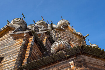 a fragment of the walls of a wooden church with domes on a blue sky background