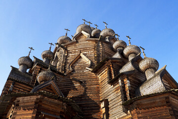 a fragment of the walls of a wooden church with domes on a blue sky background