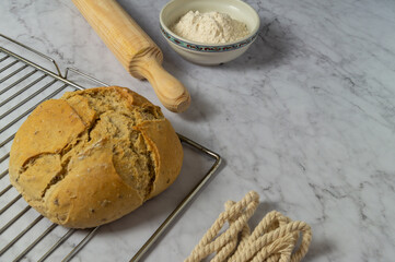 Loaf of sourdough bread on oven tray, freshly baked homemade, natural ingredients, freshness, flour, top photo, white marble background, space for text.