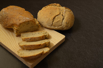 
sourdough bread slices on wooden board, freshly baked homemade, natural ingredients, freshness, flour, top photo, black background, space for text.