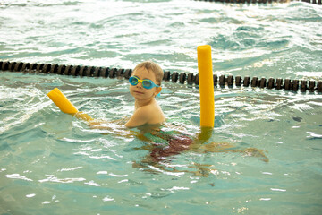 Child, taking swimming lessons in a group of children in indoor pool