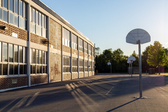 School building exterior and school yard with basketball court in the evening