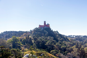 Fototapeta na wymiar The Pena Palace on the top of a green hill in the Sintra Mountains in a clear day with blue sky, Portugal, Europe