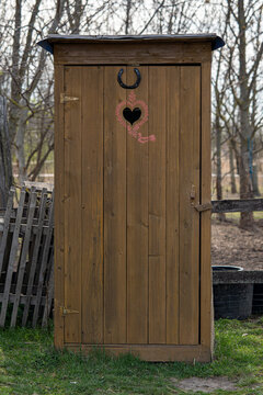 old wooden door of an old school toilet, heart and horseshoe on top, countryside