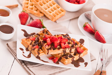 Waffles with strawberries and chocolate cream.