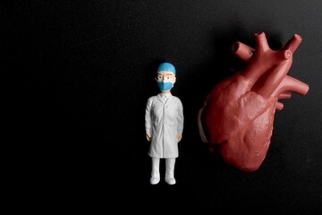 miniature figurine of a cardiologist doctor with a giant heart on a black background