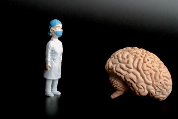 miniature figurine of a surgeon doctor with a giant human brain on a black background