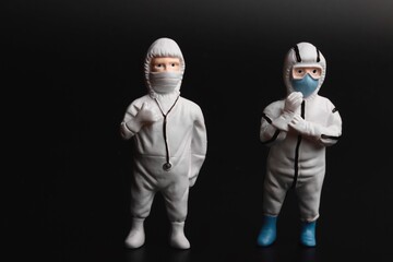miniature people with protective suits and masks on a black background
