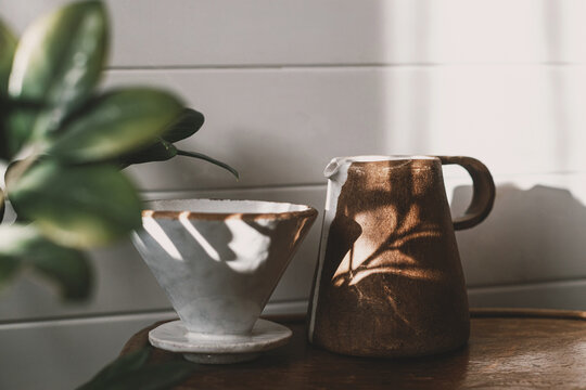 Morning coffee aesthetics. Modern ceramic cup, kettle and dripper for pour-over coffee in sunlight