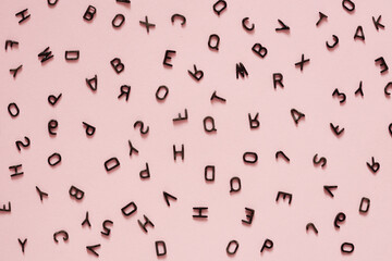 small black letters of the English alphabet scattered randomly on a pink background