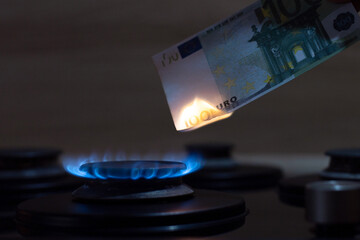 100 euro banknote burns on a gas stove, expensive gas and energy in Europe, the concept of...