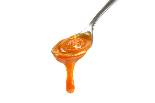 Liquid caramel on spoon. Caramel drips from the spoon. Pouring sweet caramel sauce. Texture, Close up.