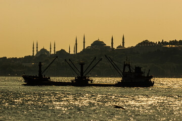 Hagia Sophia and Blue Mosque background on sunset with boat at Bosphorus strait.