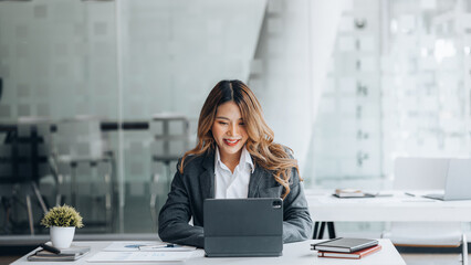 A businesswoman is checking company financial documents and using a tablet to talk to the chief financial officer through a messaging program. Concept of company financial management.