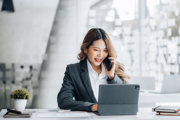 Asian woman talking on the phone, she is a salesperson in a startup company, she is calling...