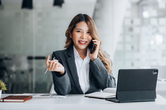 Asian woman talking on the phone, she is a salesperson in a startup company, she is calling customers to sell products and promotions. Concept of selling products through telephone channels.