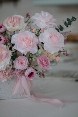 Beautiful bouquet of peonies and pink roses on the table. In the background is the interior of a modern white kitchen. Concept of home comfort.