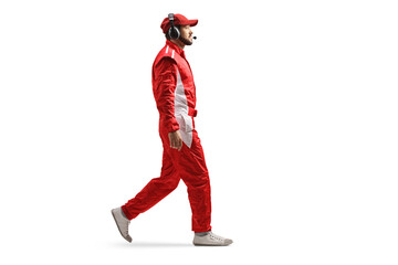 Full length profile shot of a race team member with headphones and a red suit walking