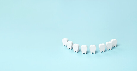 Teeth models standing in a row making a smile on a blue background. Dental banner background....