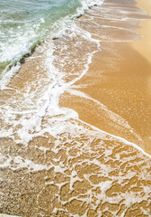 Sandy beach with boulders and sea foam. Natural sea landscape photo.