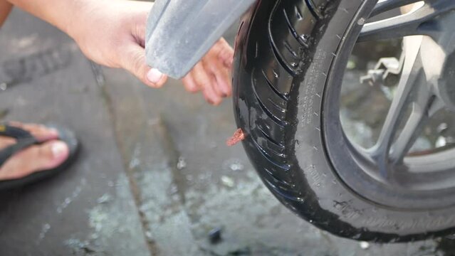 Hands of man repairing flat motorcycle tire with repair kit. Tire plug repair kit for tubeless tires.