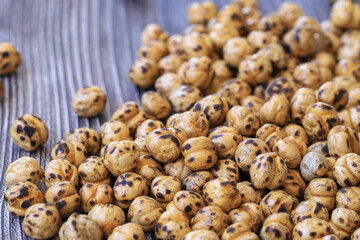 Roasted spicy chickpeas , yellow chickpeas on wooden background .
