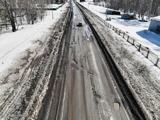 Broken old asphalt road outside the city. Pits and potholes. Aerial view