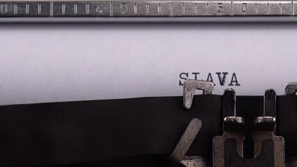 Typing Ukrainian greeting and slogan "SLAVA UKRAINI ! HEROIAM SLAVA !" on retro typewriter. - Powered by Adobe